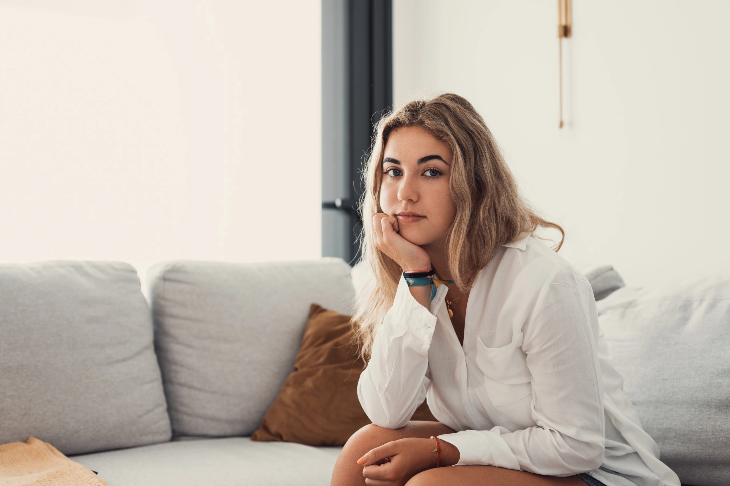 young woman sitting on a couch with a contemplative look